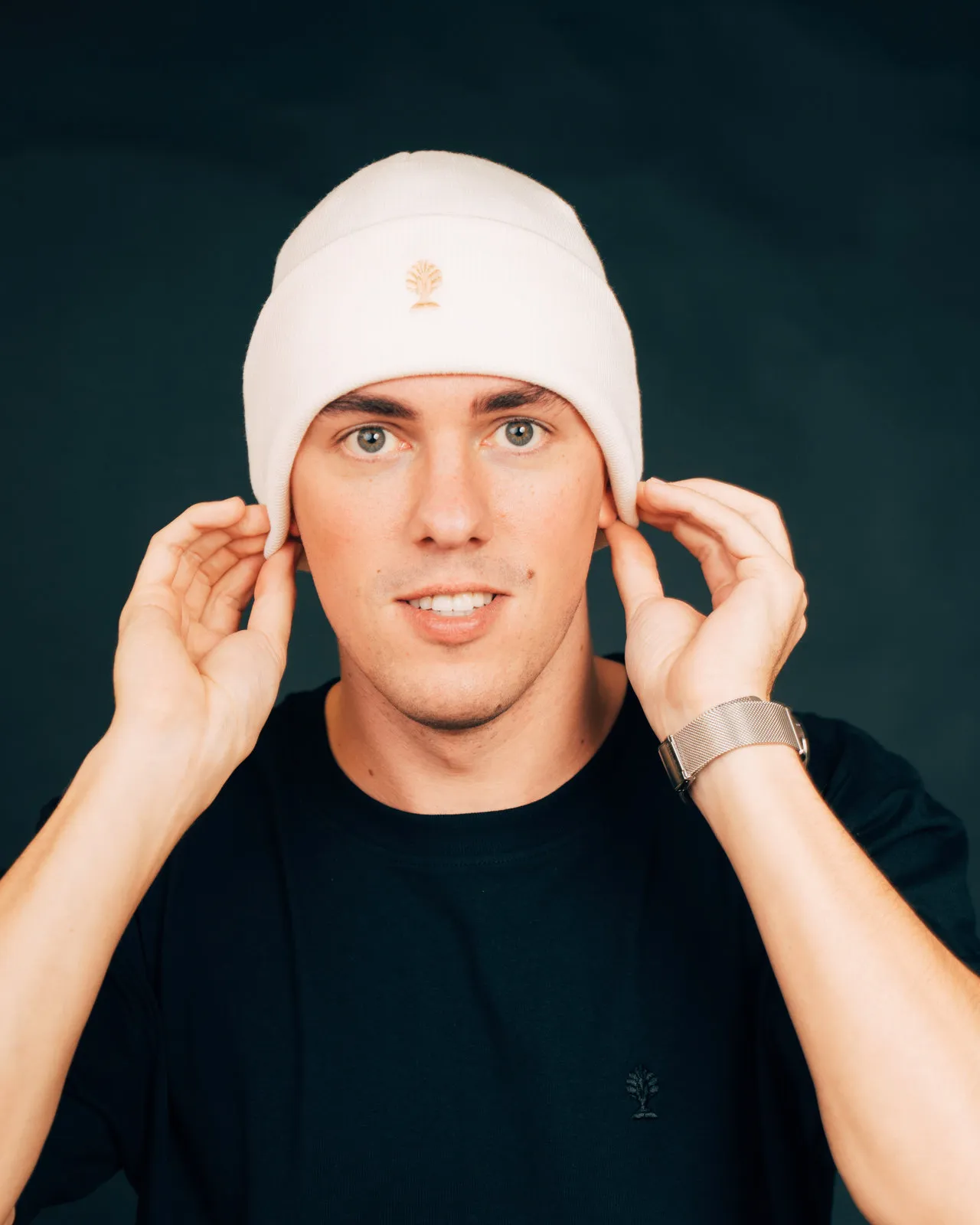 Merino-Beanie in creme mit goldenem Logo, getragen