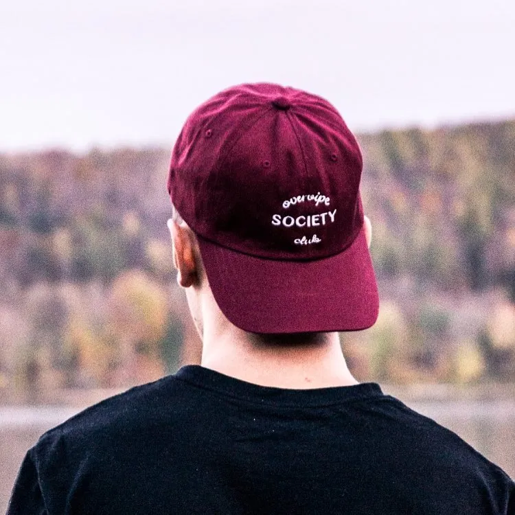 Bordeauxrote Cap mit „OVERVIPE Society“ vor herbstlichem Wald